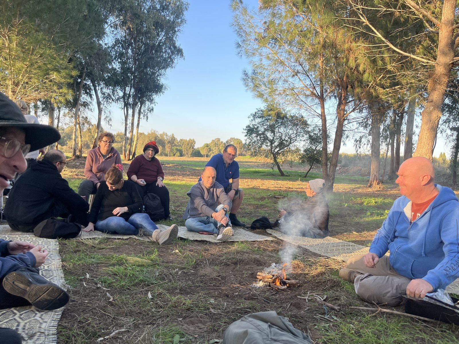 קבוצת צא בחוץ יושבת יחד סביב מדורה בטבע